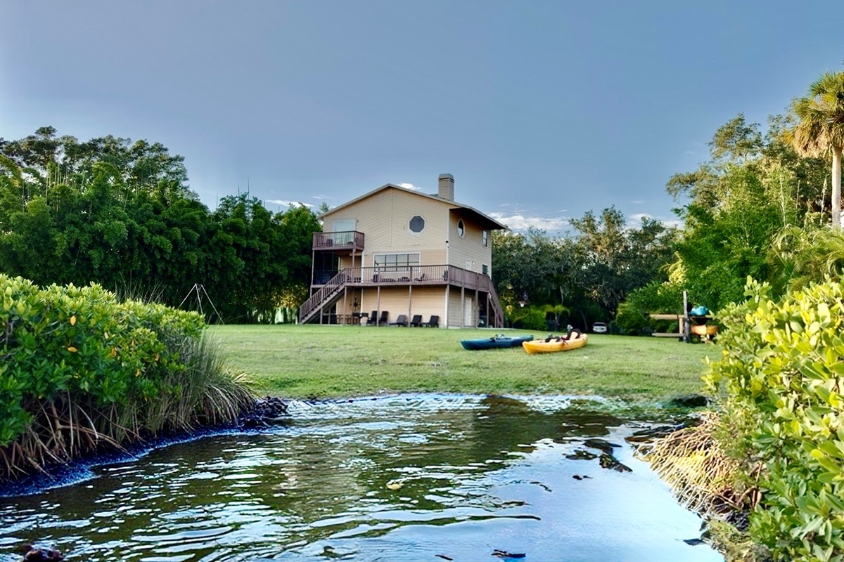Waterfront home with elevated deck and cozy seating.
