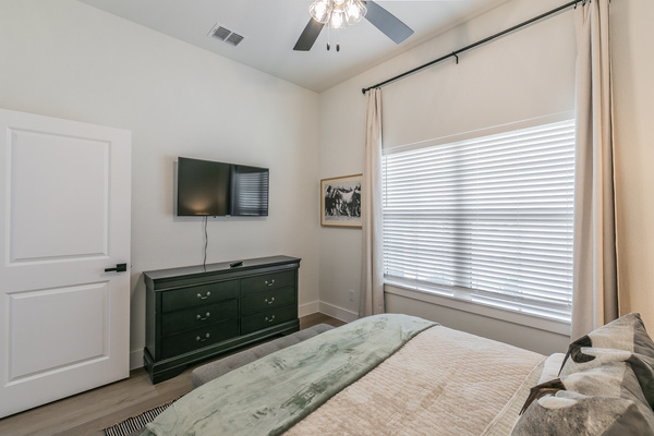 The Fort Worth Room with queen bed, smart TV, ceiling fan and clothing storage