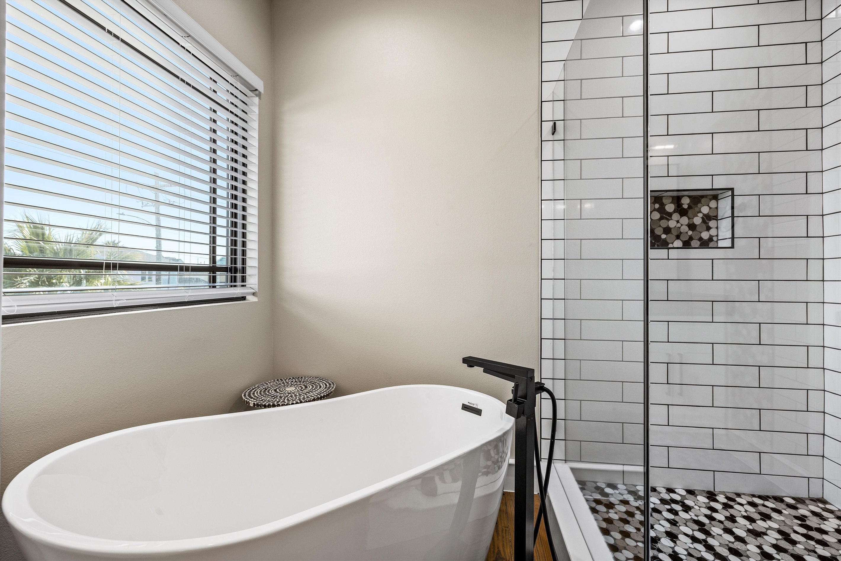 Bathroom Bliss: Indulge in a spacious tub with chic decor and refreshing natural light!