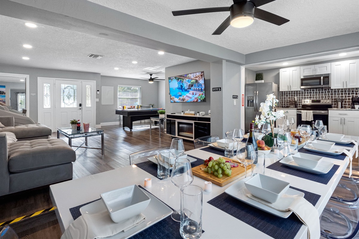 This sleek dining area features a modern white table with transparent chairs, perfect for large groups to gather and enjoy meals in style.