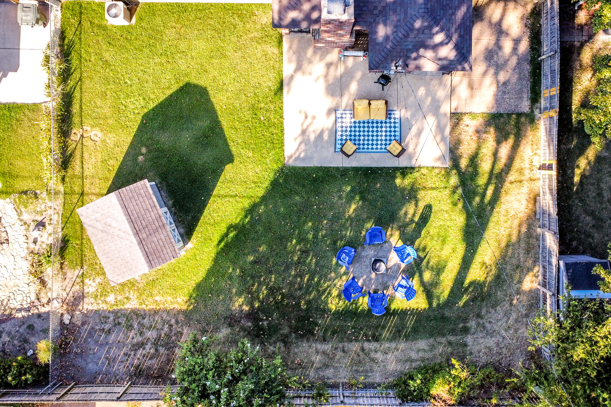 Fenced backyard with string-lit patio, fire pit, and electric grill.