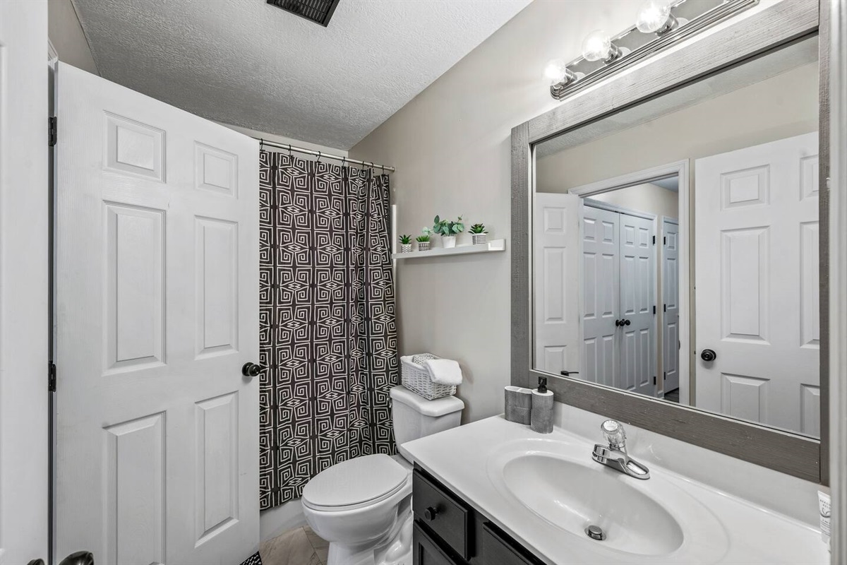 Bright and clean bathroom with a modern vanity, shower/tub combo, and fresh towels provided. Thoughtful touches like storage baskets and décor make it feel comfortable and welcoming.