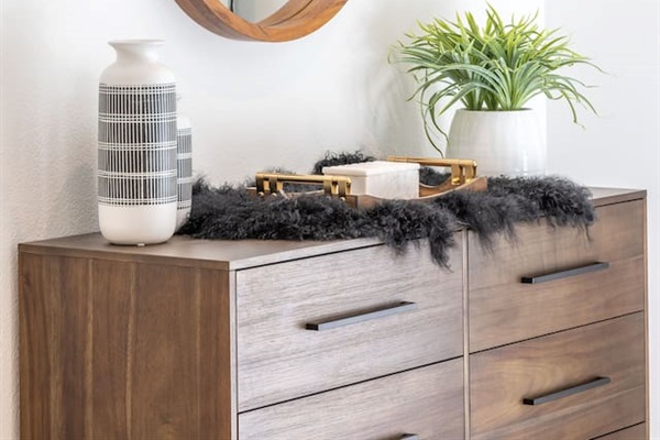 Bedroom 2 features a spacious dresser with ample storage, styled with warm wood tones and thoughtful décor. Ideal for unpacking and settling in, this piece adds both function and a polished, hotel-inspired feel to the room.