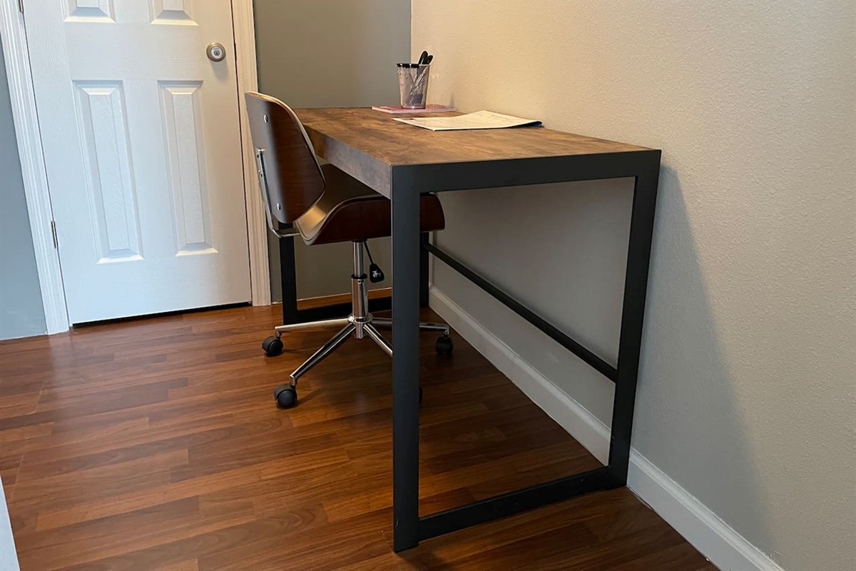 Functional workspace with a wooden desk and and office chair on hardwood floors.