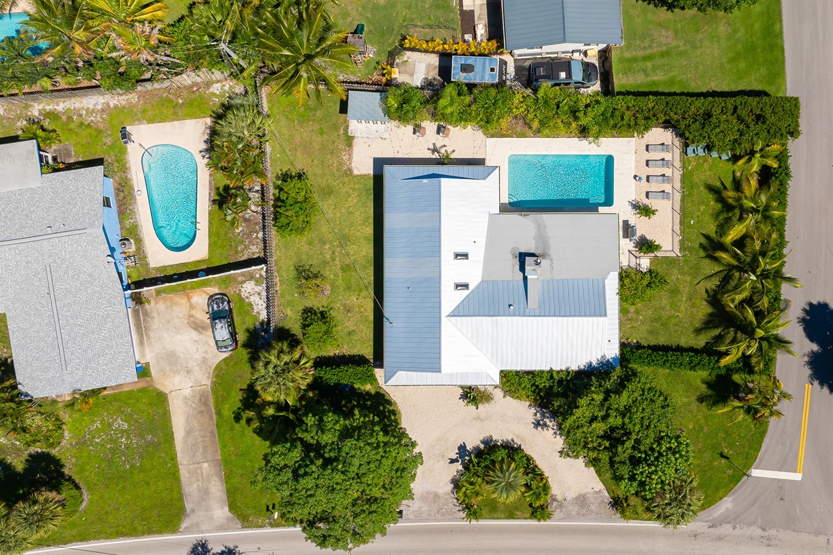A stunning aerial view captures this luxury coastal retreat with a sparkling pool, manicured lawns, and lush tropical landscaping - offering the perfect blend of privacy, sophistication, and resort-style living just minutes from the beach.