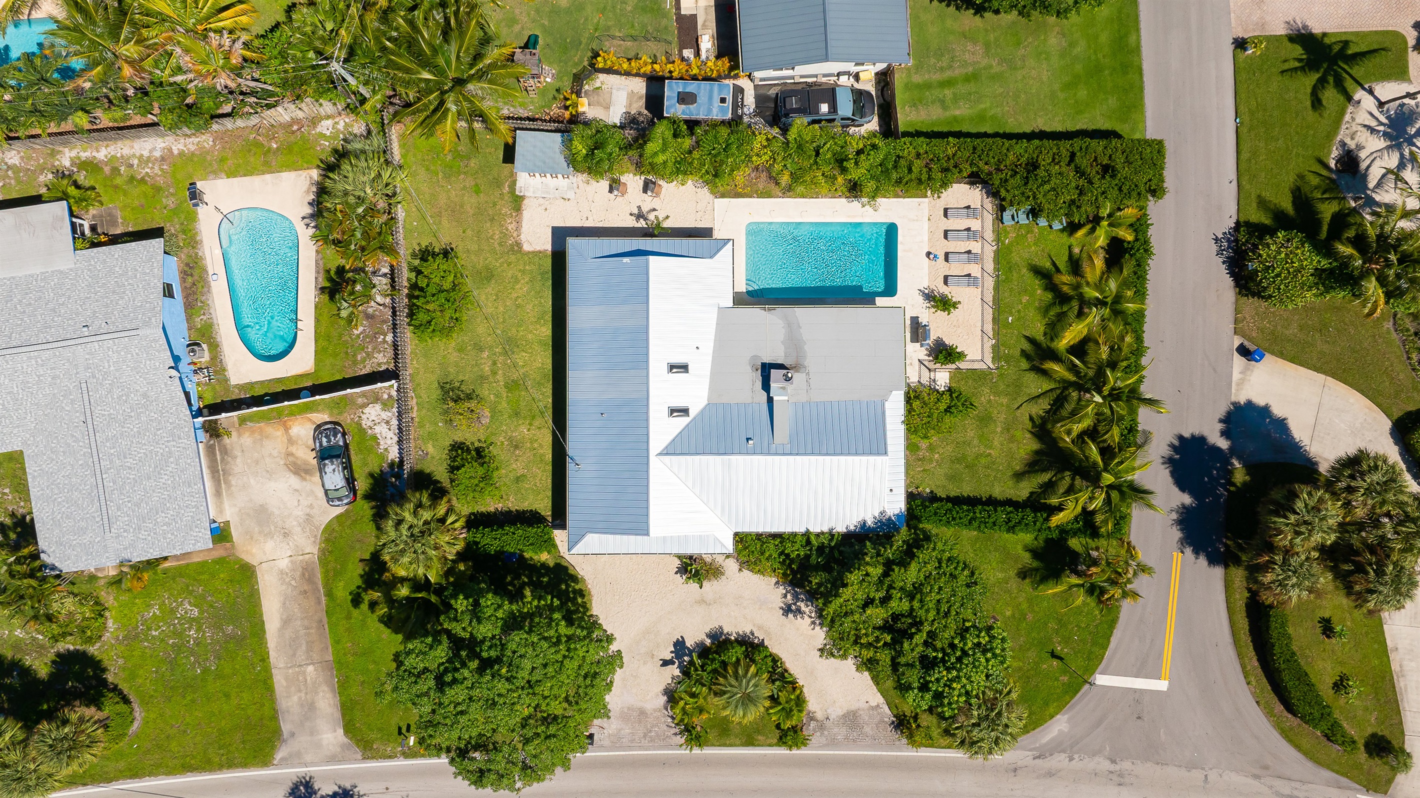 A stunning aerial view captures this luxury coastal retreat with a sparkling pool, manicured lawns, and lush tropical landscaping - offering the perfect blend of privacy, sophistication, and resort-style living just minutes from the beach.