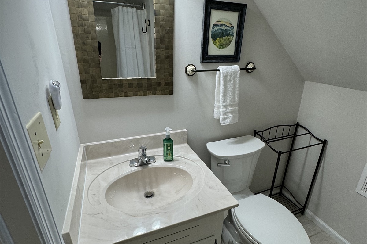 This top floor full bathroom has a shower with a curved shower rod & great storage for guests' toiletry bags! This bathroom recently had a mini-update too.