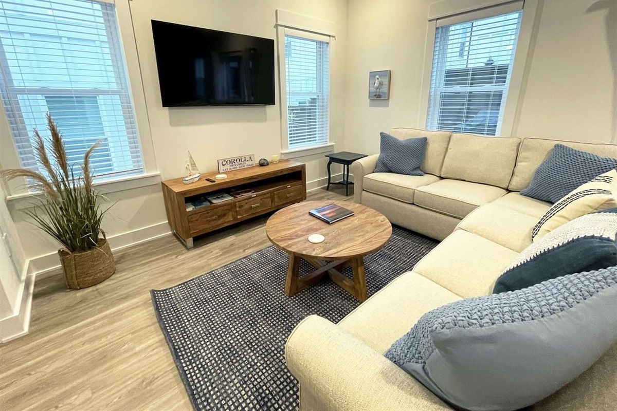 Inviting living area with plush sectional sofa, wall-mounted TV, and plenty of natural light for family movie nights or quiet evenings in.