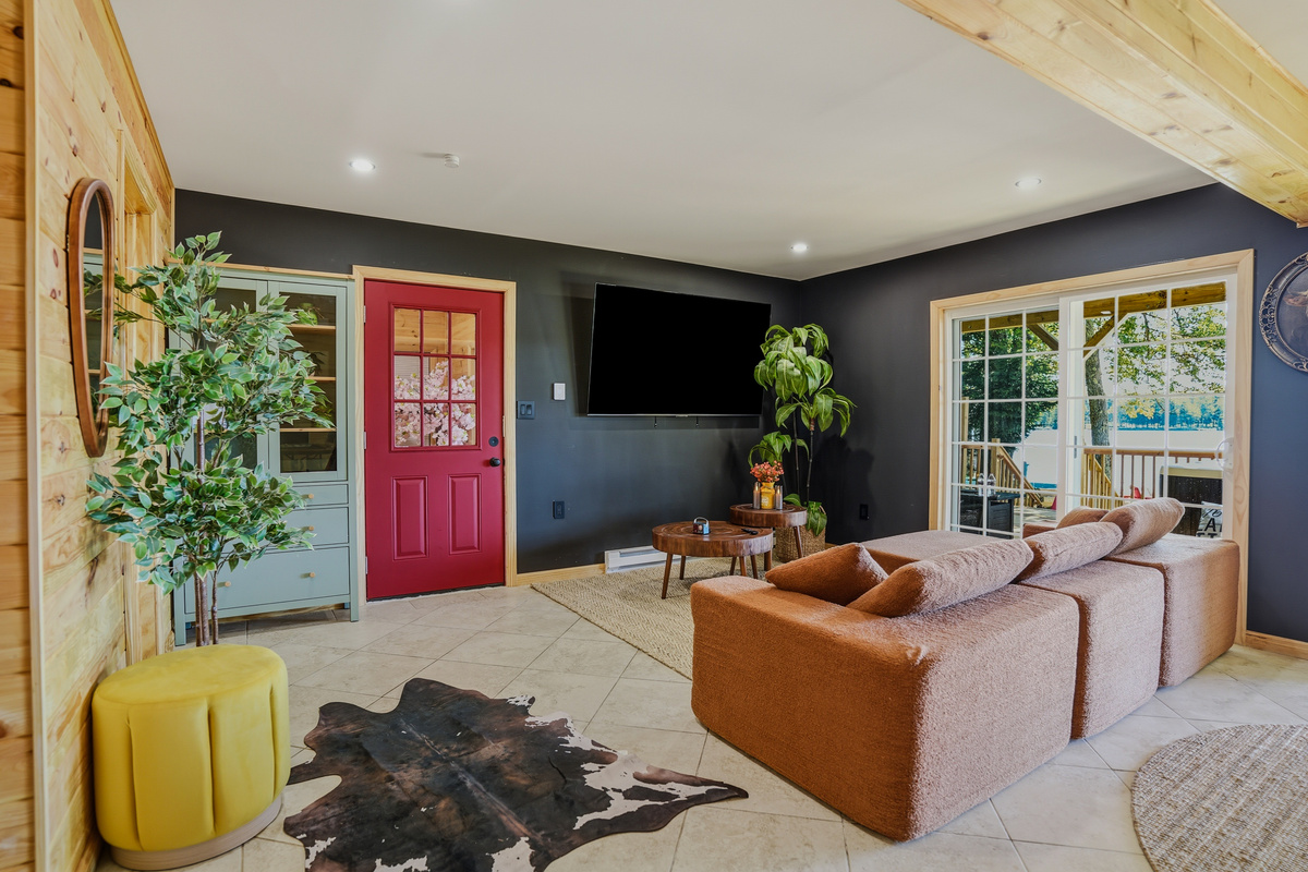 Family living room from alternate angle — leather sofa, TV, red door, and cowhide rug