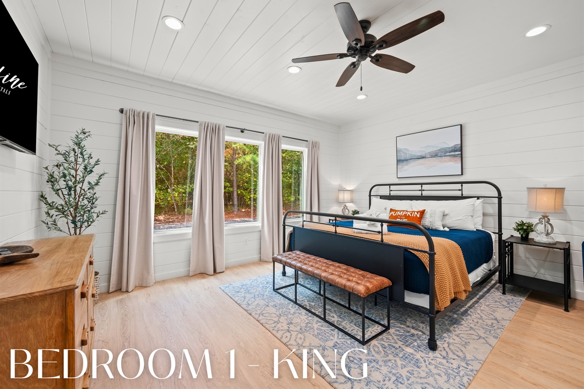 Bedroom 1 with king bed, large windows, and private bath access.