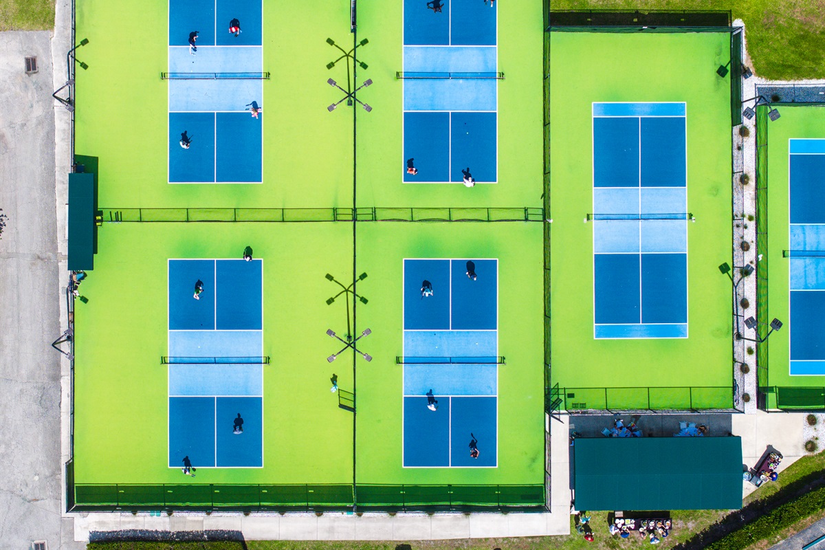 Resort amenities at PGA National feature tennis courts, pickleball courts, and a community pool surrounded by scenic lake views