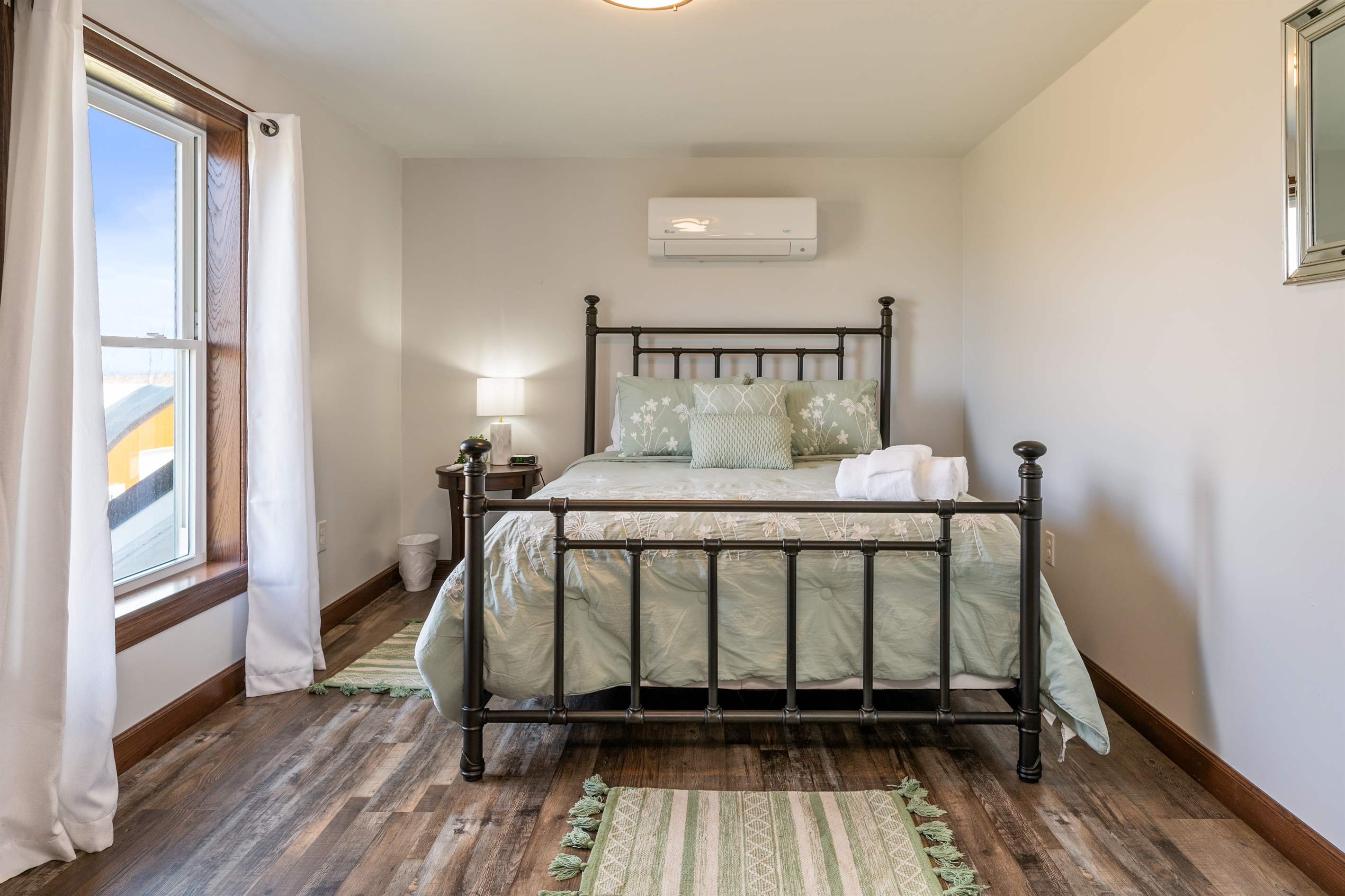 Peaceful bedroom with a queen bed and plenty of natural light—offering comfort and relaxation with a touch of rustic charm.