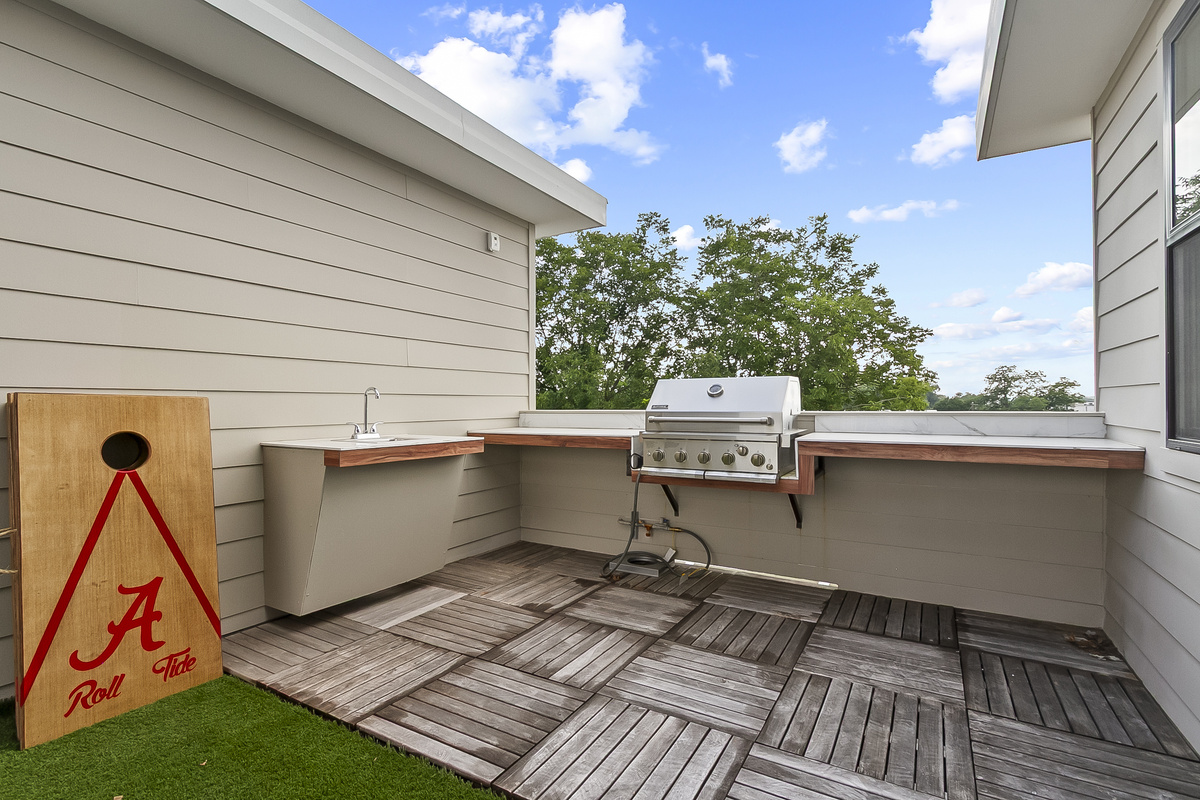Rooftop Patio with seating, Large TV, gas grill and cornhole.
