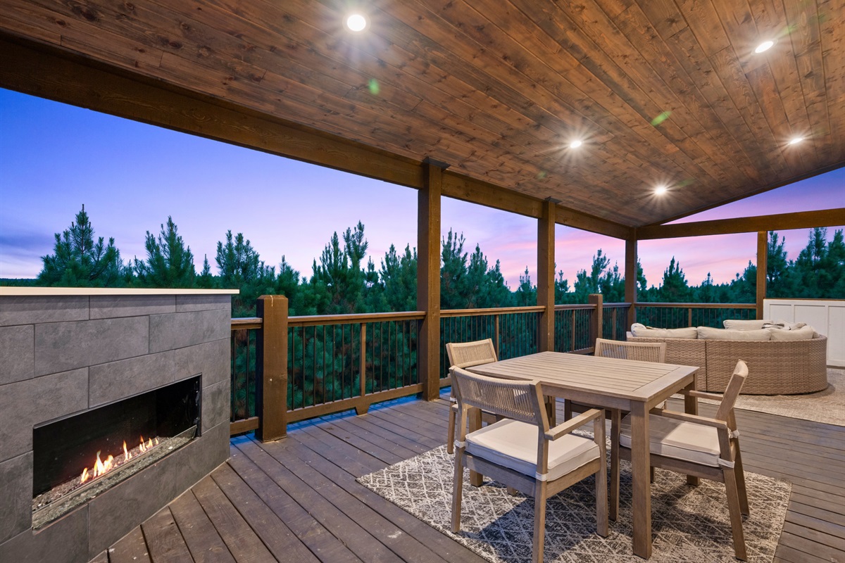 Covered deck with dining area and fireplace for year-round comfort.