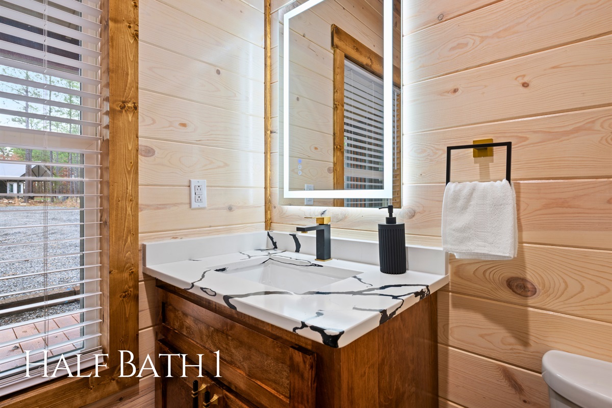 The stylish half bath on the main level offers a convenient stop for guests while maintaining the warm wood cabin aesthetic.