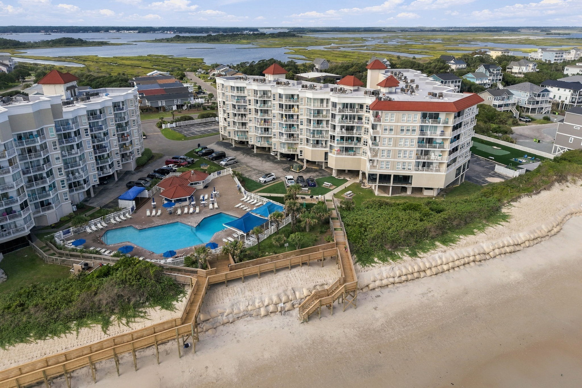Bird's-eye view of the resort complex, highlighting the outdoor pool area and scenic coastline.