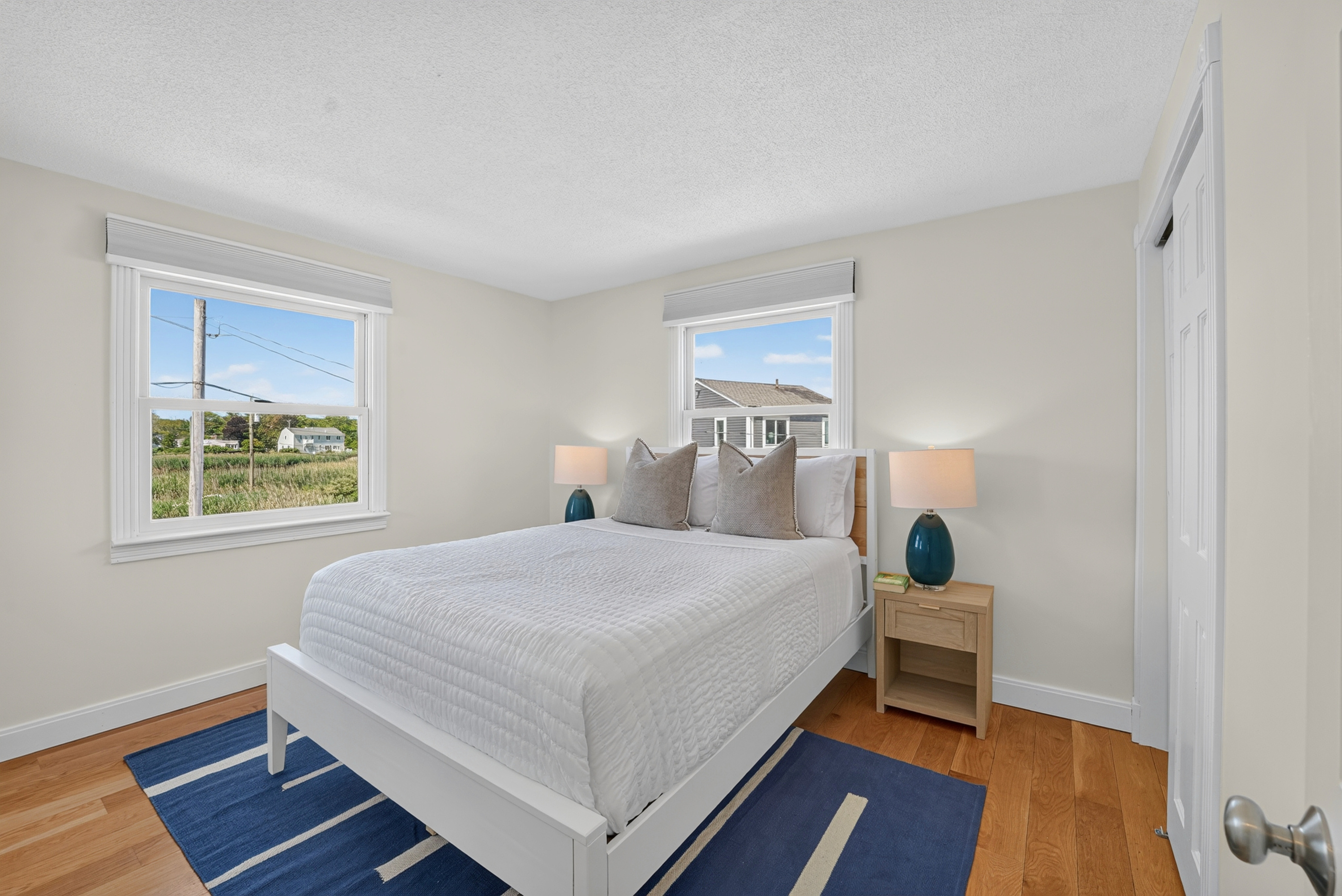 Inviting bedroom with windows on two sides for abundant natural light and refreshing coastal scenery.