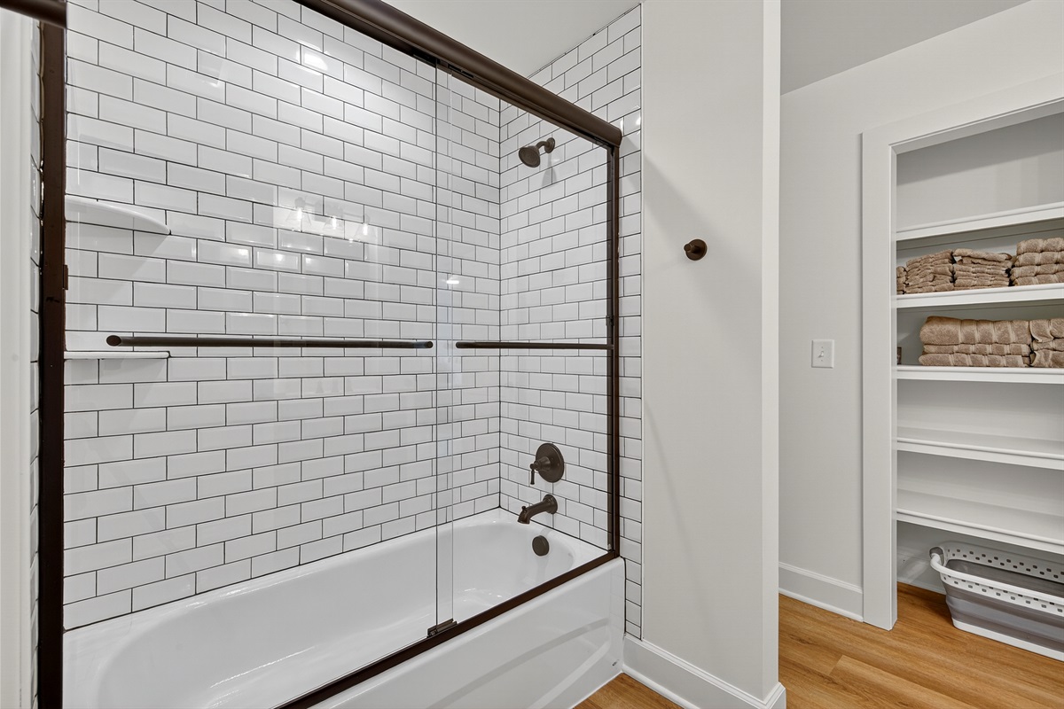 Stylish tub/shower combo with sleek subway tile and modern fixtures.