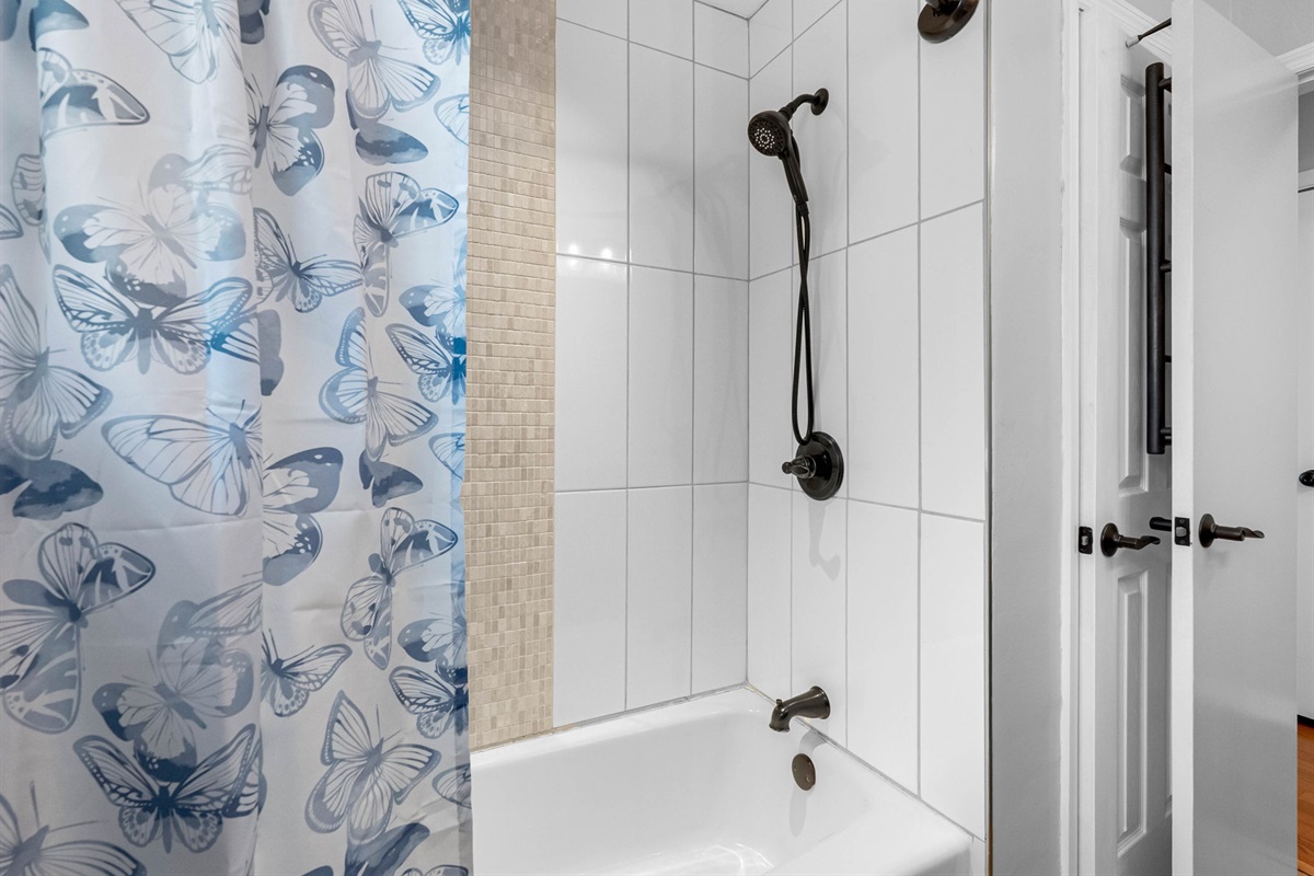 Designed for comfort and convenience, this full bathroom features a classic tub and shower setup with kid-friendly touches and a lighthearted butterfly curtain that appeals to guests of all ages.