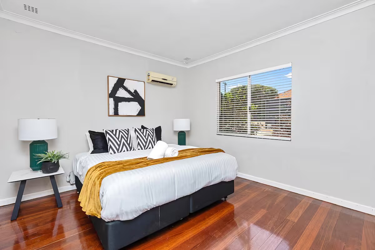 The king bed, bedside tables, lamps and timber floors give this bedroom at Sasha’s Cottage on the Hill a practical guest setup.