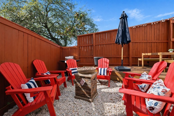 Fully fenced private backyard featuring a spacious deck and gravel lounge area with Adirondack seating around a fire feature. Enjoy outdoor dining, string lights for evening ambiance, and plenty of space to relax or gather with family and friends