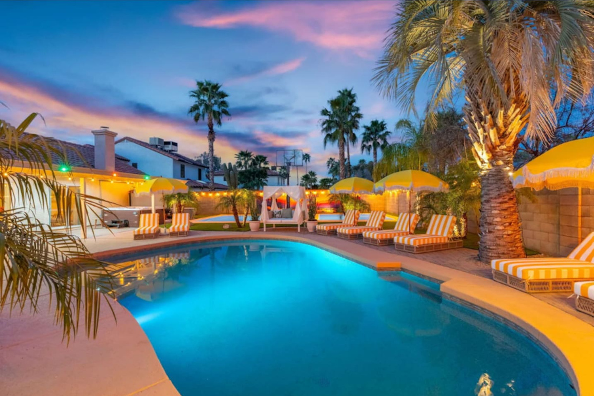 Twilight hues wash over the pool and loungers, framed by the softly lit home.
