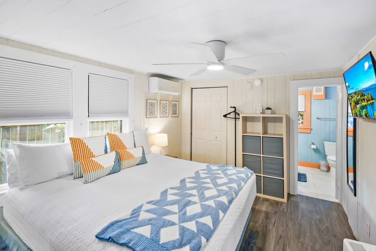 King bed, crisp white linens and daylight coming in from two sides. A futon in the same room folds out to a full-size bed, which is how a third guest fits in comfortably without anybody feeling squeezed.
