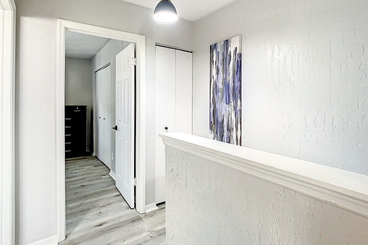 Hallway with warm wood cabinetry and neutral walls, featuring elegant lighting and spacious design.