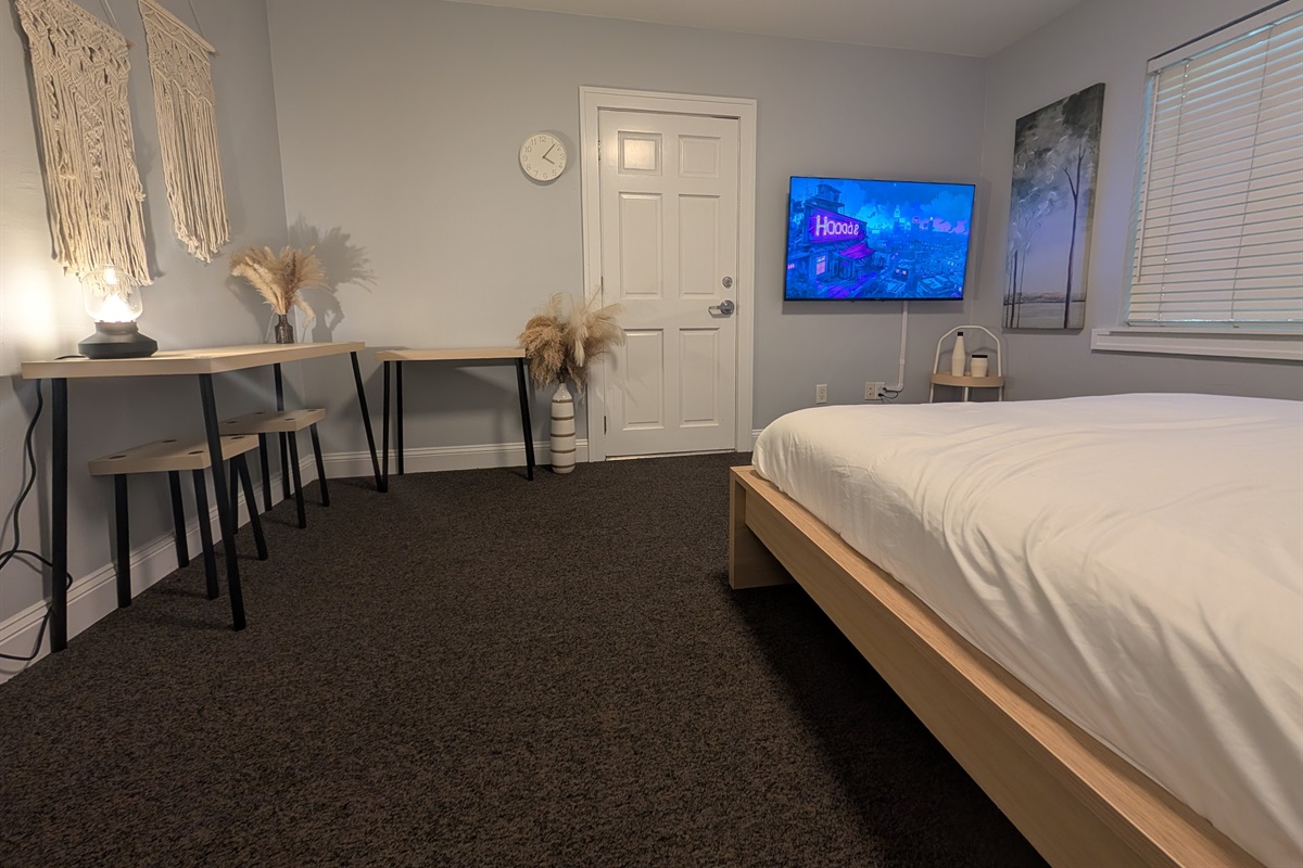 Guest bedroom with queen bed, desk and smart tv