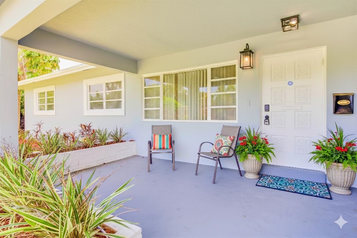 Charming front porch with cozy seating, lush plants, and a welcoming entry—perfect for morning coffee or quiet moments outdoors.