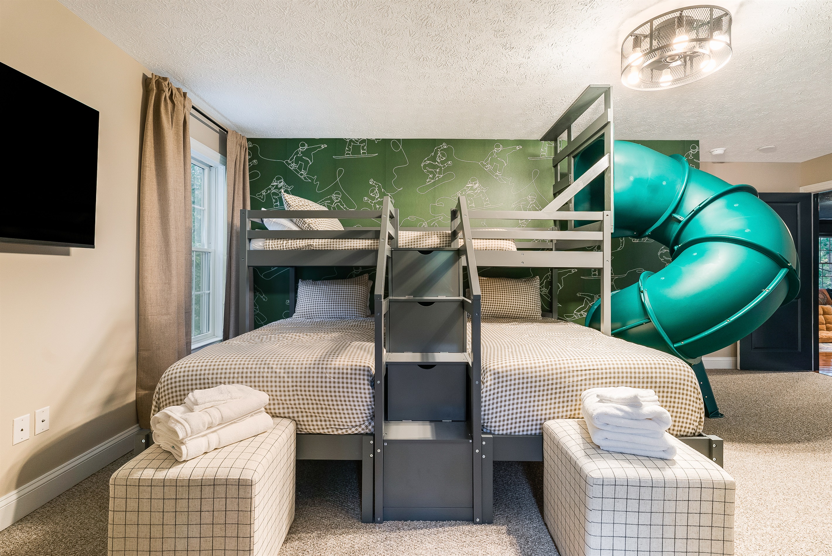 Double bunk setup with TV and playful snow-sport mural, designed for fun sleepovers.