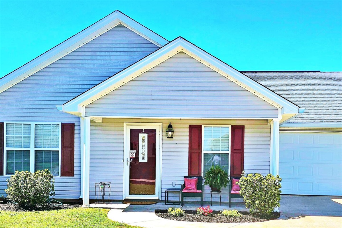 Welcome to A Southern Charm, a homey home. There is a front porch with seating and a table. 