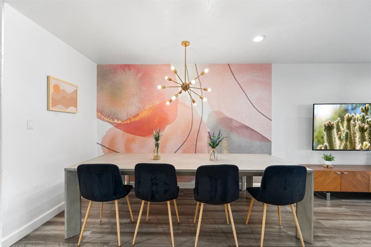 Sleek black chairs, a warm-toned mural, and natural wood textures offer a blend of comfort and curated style.

