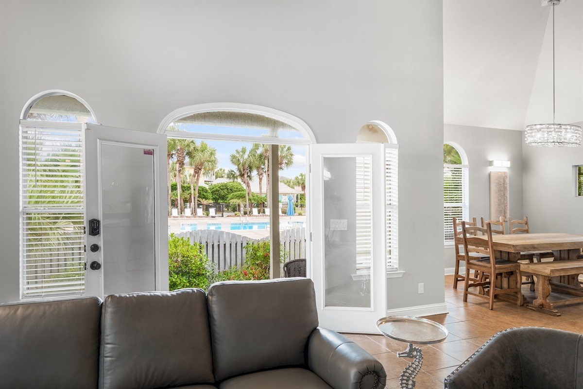 Bright living room with French doors opening to pool views
