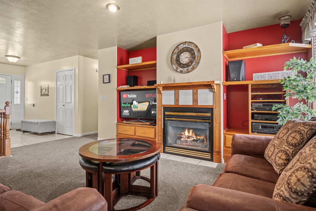Bright, comfortable main-level living space featuring plush seating, fireplace, and entertainment center.