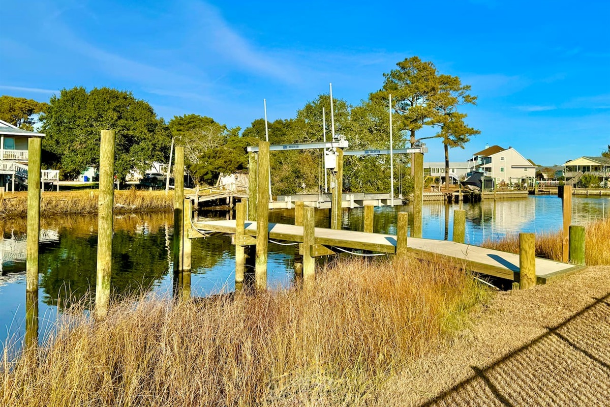 Private backyard dock with boat lift and fillet table, fenced-in backyard, fire pit with Adirondack chairs, hammocks, propane grill, picnic table, outdoor shower, expansive waterfront back deck with table and seating, neighborhood boat ramp and dock