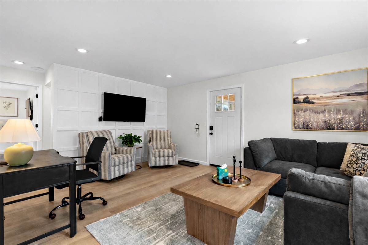 Enjoy this bright living room with comfortable seating, a smart TV, and a dedicated workspace—perfect for relaxing, working, or entertaining with ease.