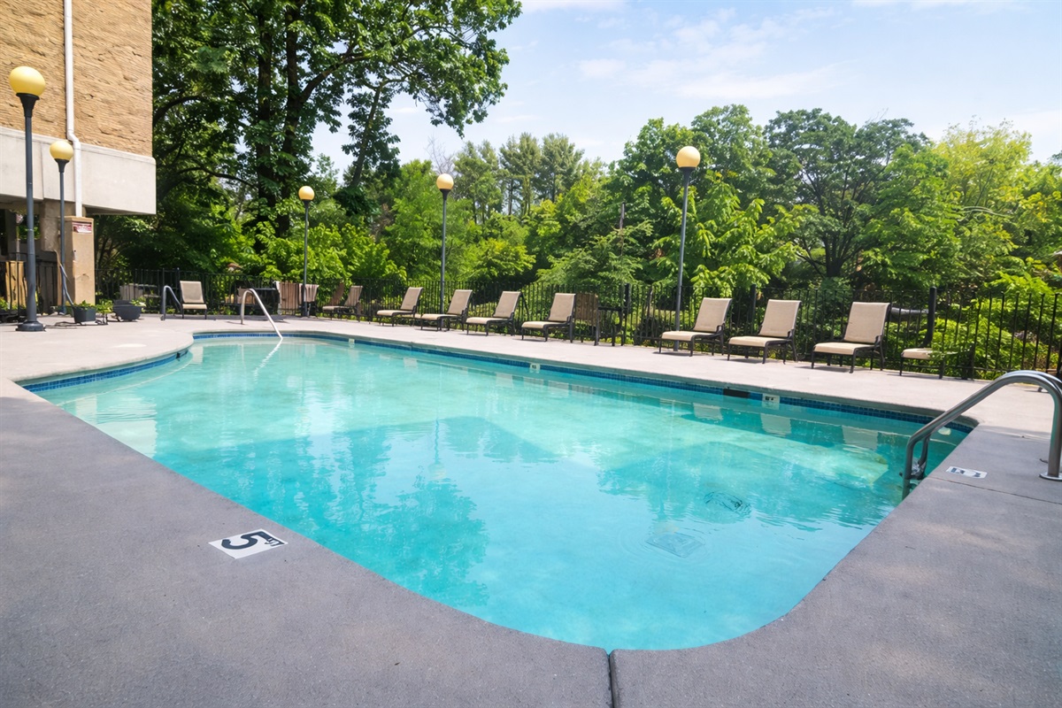 Seasonal outdoor pool surrounded by lush trees — enjoy resort-style amenities just steps from your condo.