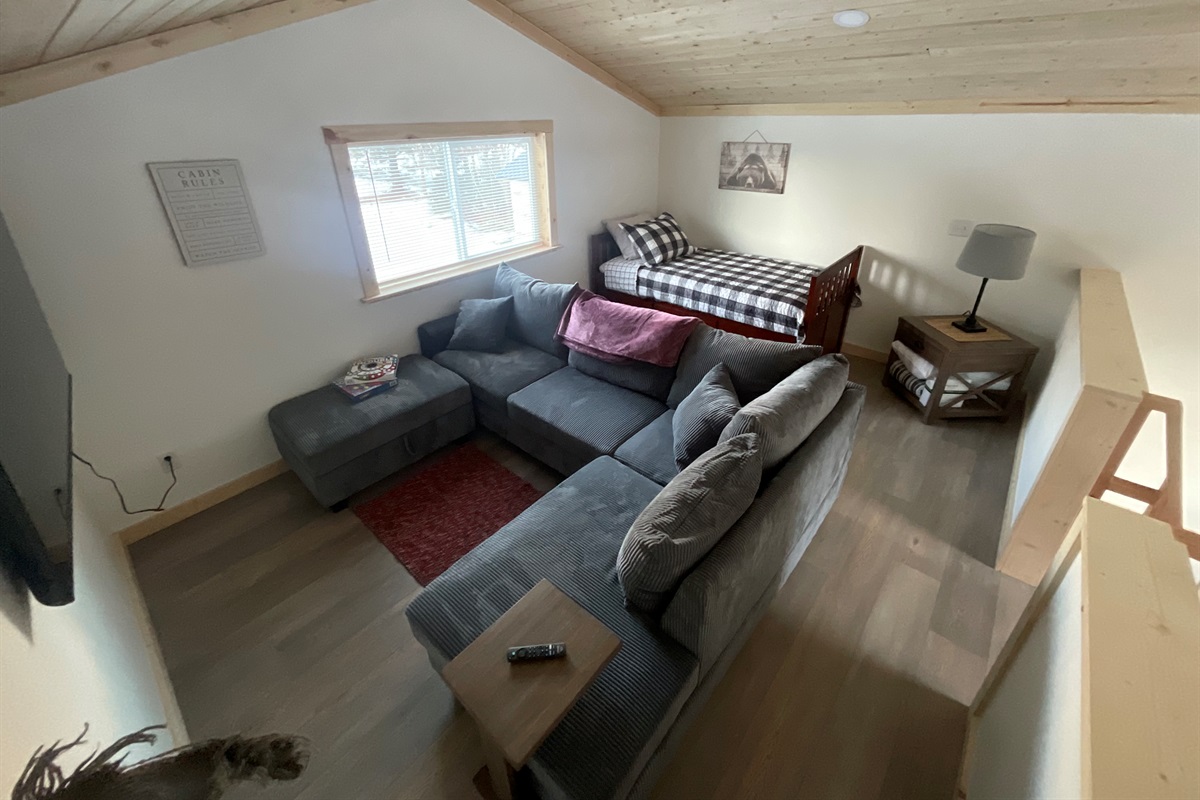 Loft area includes sectional sofa and additional bed (twin bed with trundle bed) [Photo is representative but may not be from this cabin].