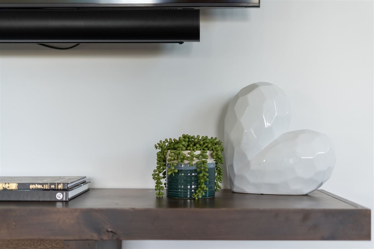 The console table under the TV adds functionality and style, featuring yoga mats, books, and decorative accents that enhance the room's relaxed atmosphere.
