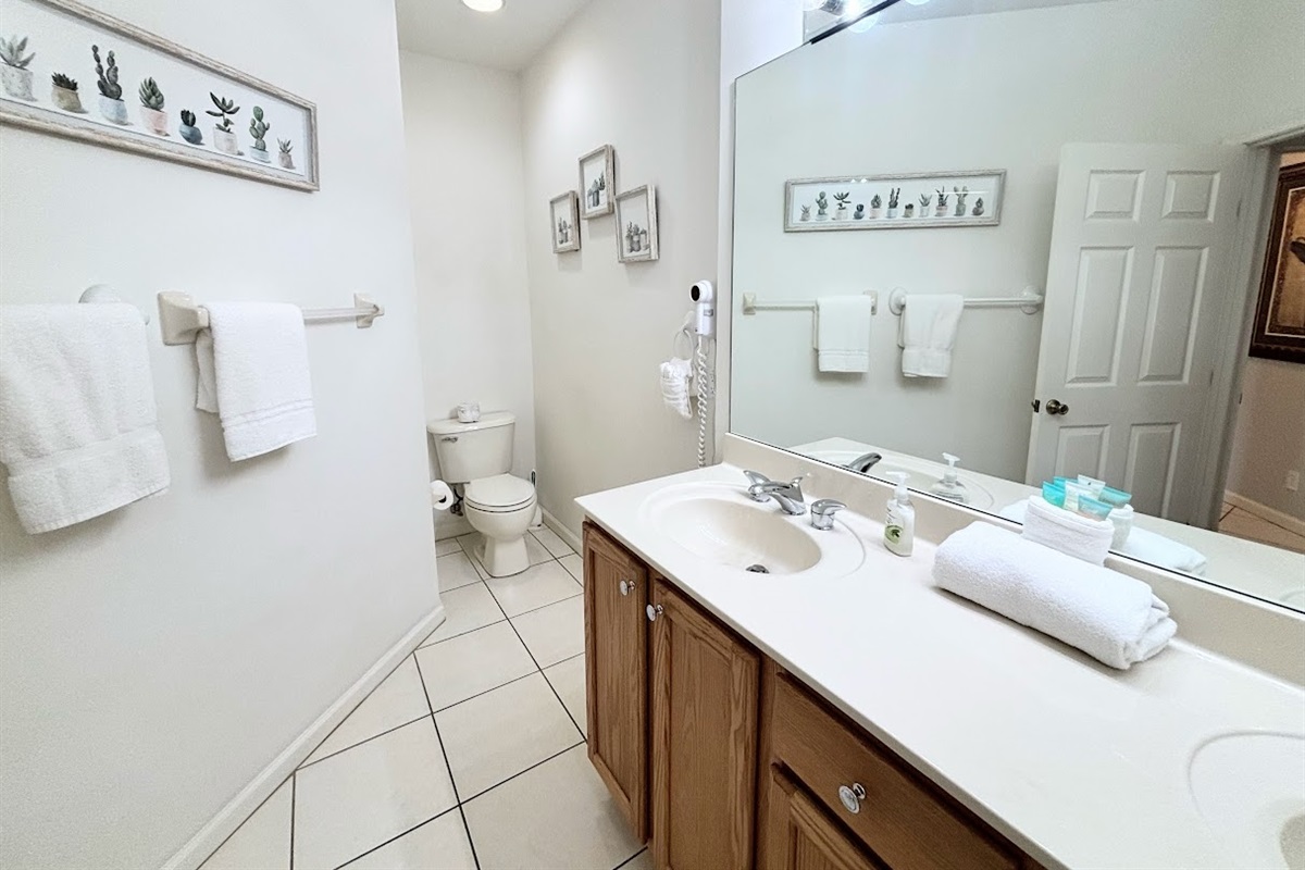 Spacious bathroom with a large vanity, full mirror, tile flooring, and plenty of counter space.