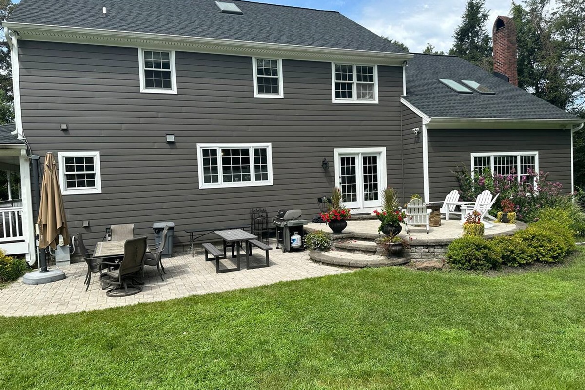 Back of the house. See multiple dining tables,  large grill, firepit, and large cantilever umbrella which provides lots of shade from the sun when extended. 