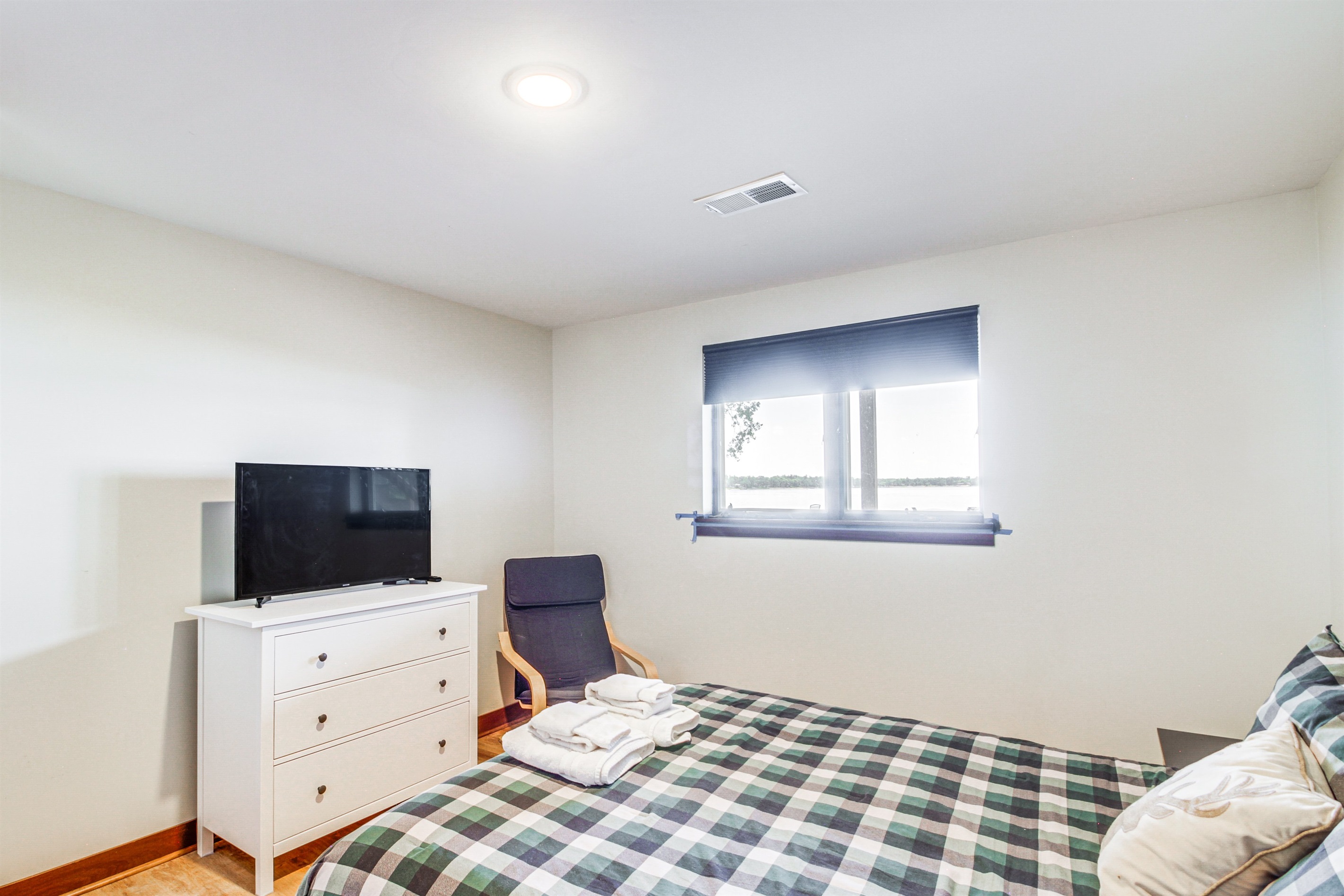 Lower-level bedroom with queen bed, dresser, and TV for private relaxation