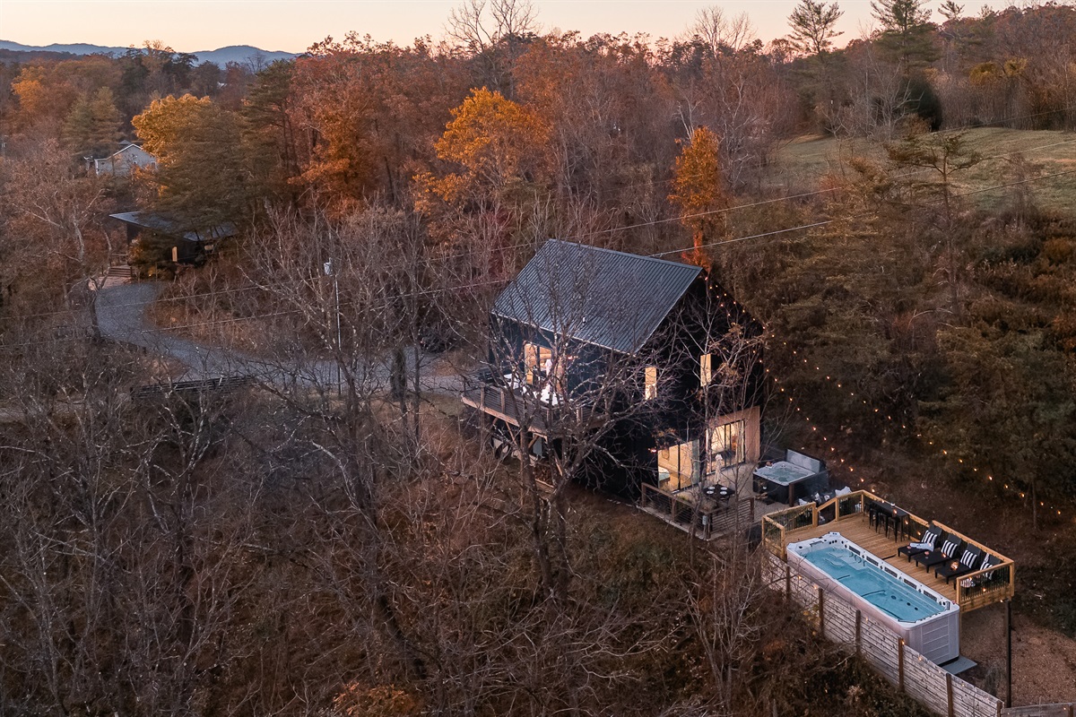 {Estate Aerial} Gallery House illuminates the hillside with warm string lights, with Glass House tucked just beyond—twin estates set amid rolling hills and Blue Ridge vistas, all moments from