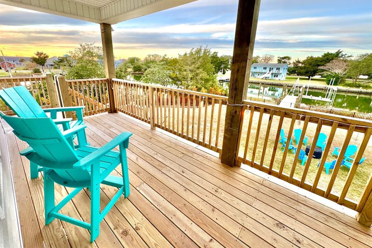 Private backyard dock with boat lift and fillet table, fenced-in backyard, fire pit with Adirondack chairs, hammocks, propane grill, picnic table, outdoor shower, expansive waterfront back deck with string lights, neighborhood boat ramp