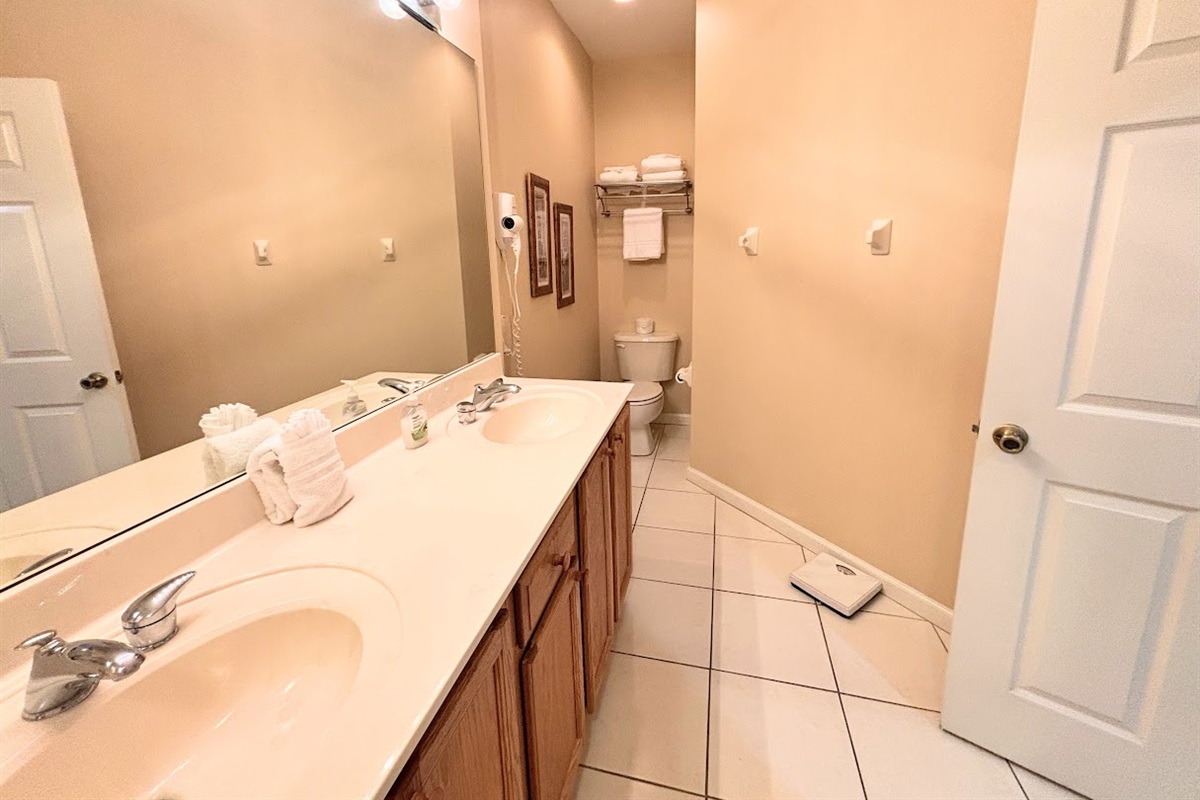 Clean and spacious bathroom featuring a large vanity, bright mirror lighting, tile flooring, and plenty of counter space.
