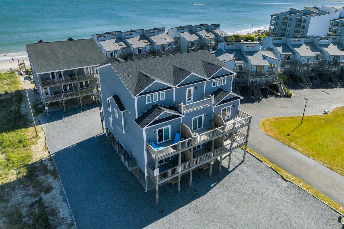 Dramatic overhead drone perspective emphasizing the townhouse's architectural roofline, direct beachfront position, and expansive views across the Atlantic.   