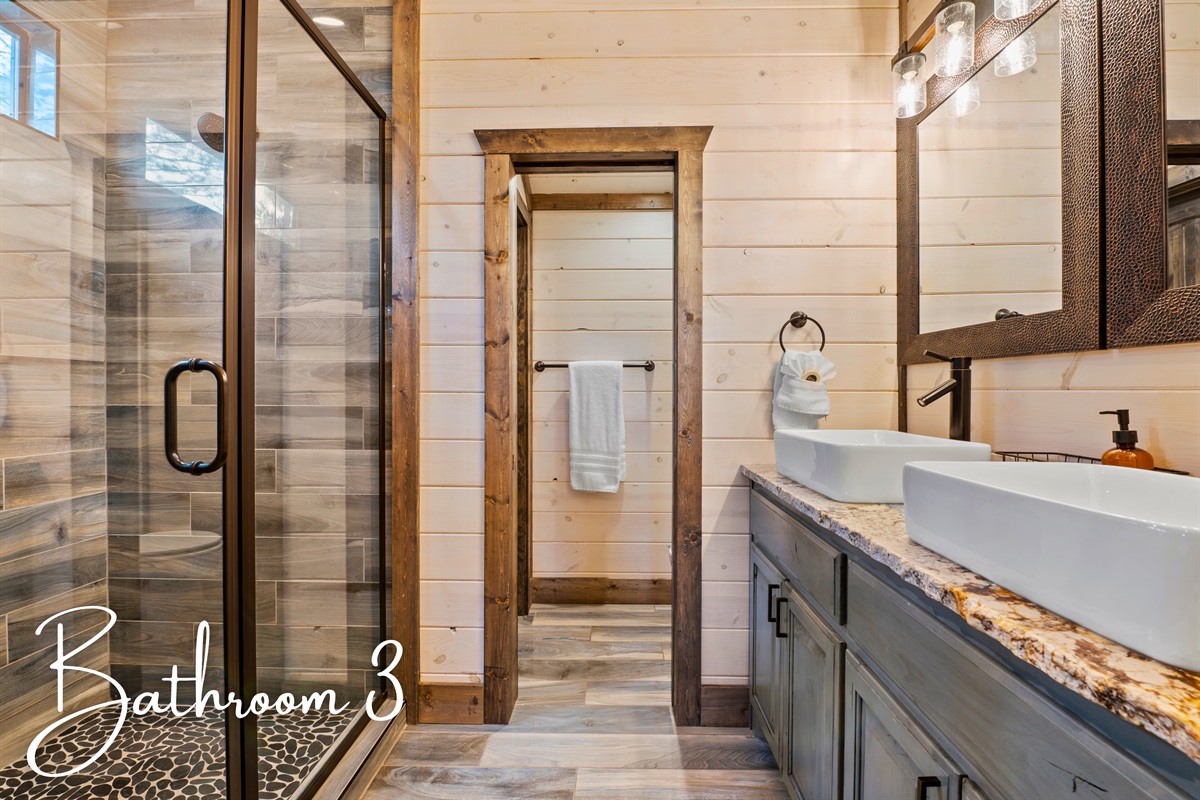 The bathroom is equipped with a walk-in shower and a vanity that beautifully mixes modern design with natural elements.
