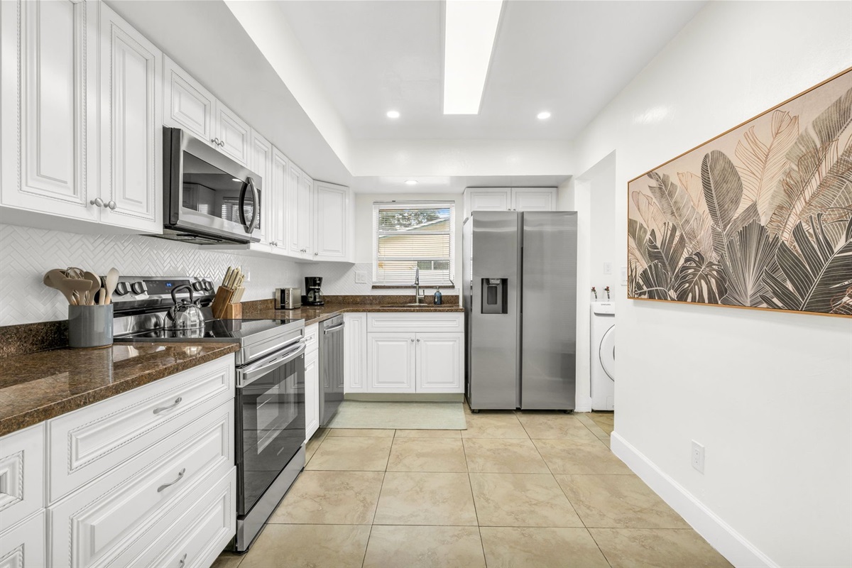 A spacious, light-filled kitchen offering stainless steel appliances, rich countertops, extensive cabinetry, and thoughtful amenities such as a coffee maker, blender, and toaster for effortless cooking and entertaining.
