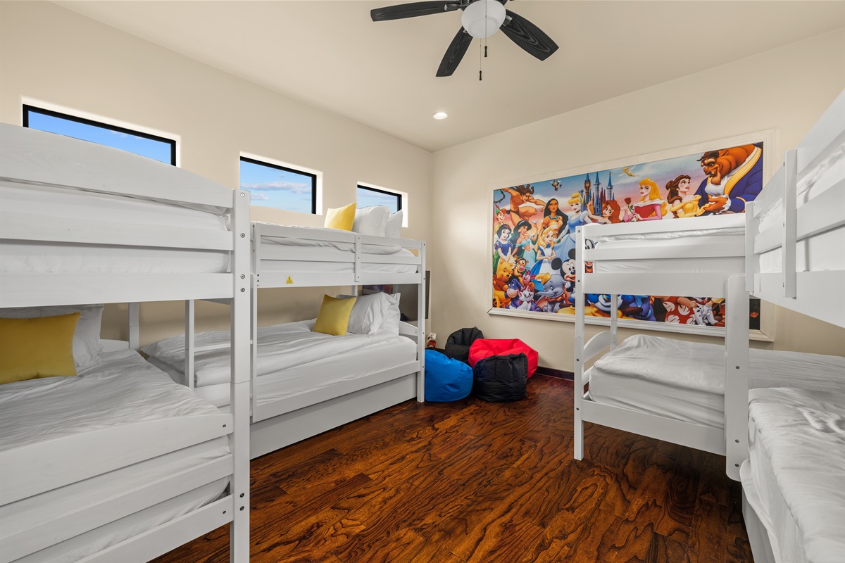Bedroom 4 "Welcome to the ultimate bunk room! Featuring 10 twin beds, a fun gaming station, and vibrant Disney artwork, this space is perfect for kids and kids-at-heart to create unforgettable